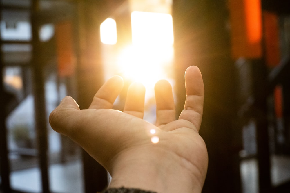 force perspective photography of left human hand and sun