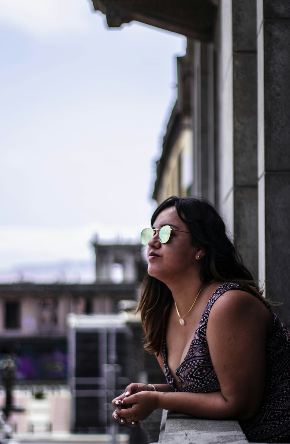 woman wearing purple and white tank dress leaning on ledge during daytime