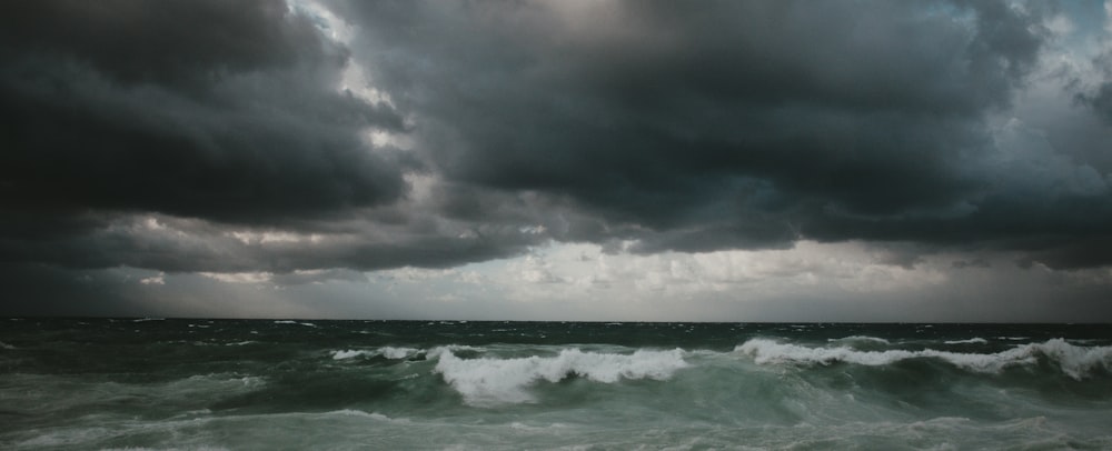 a stormy sky over the ocean with a boat in the water