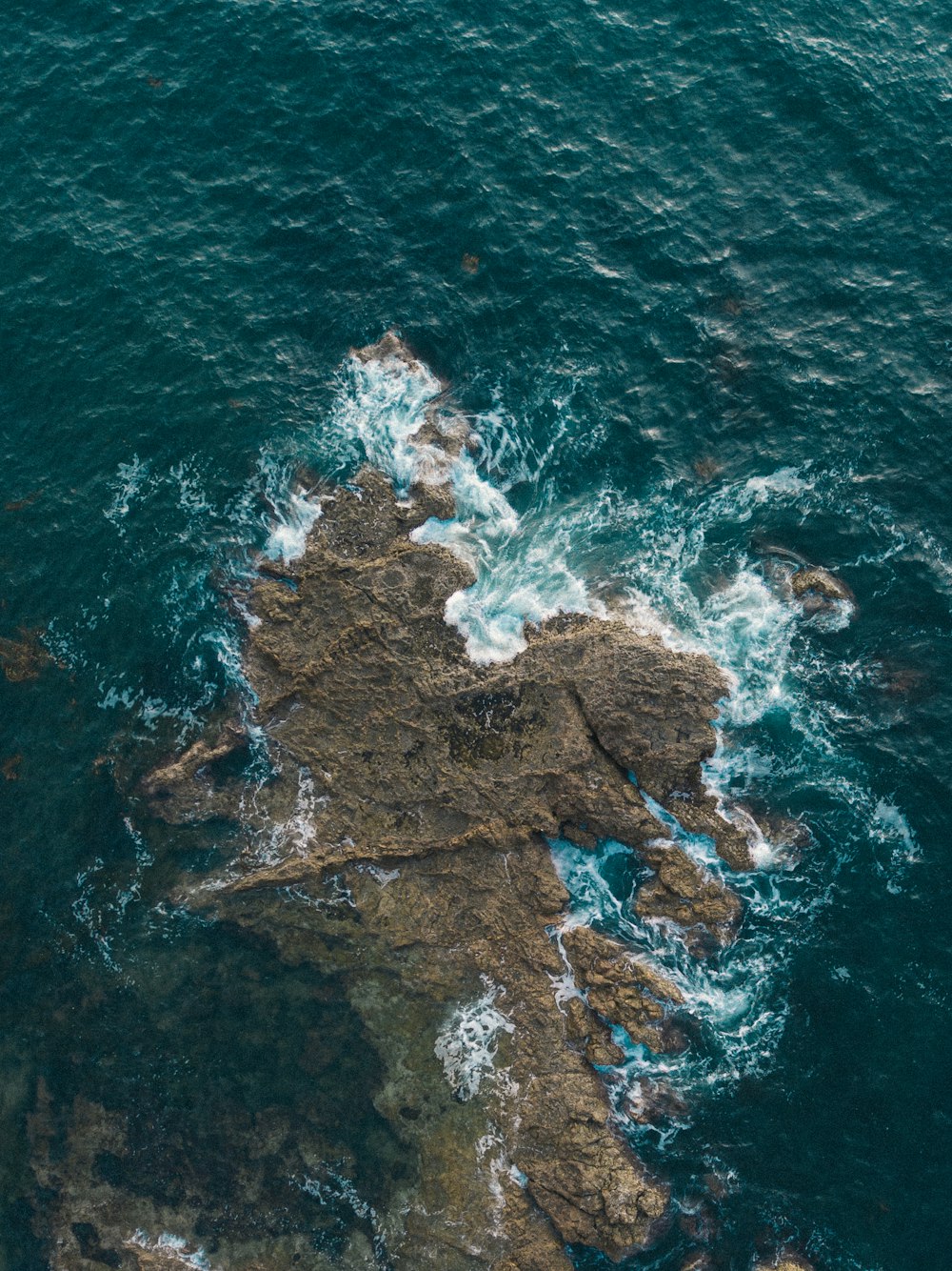 rock formation on shallow water during daytime