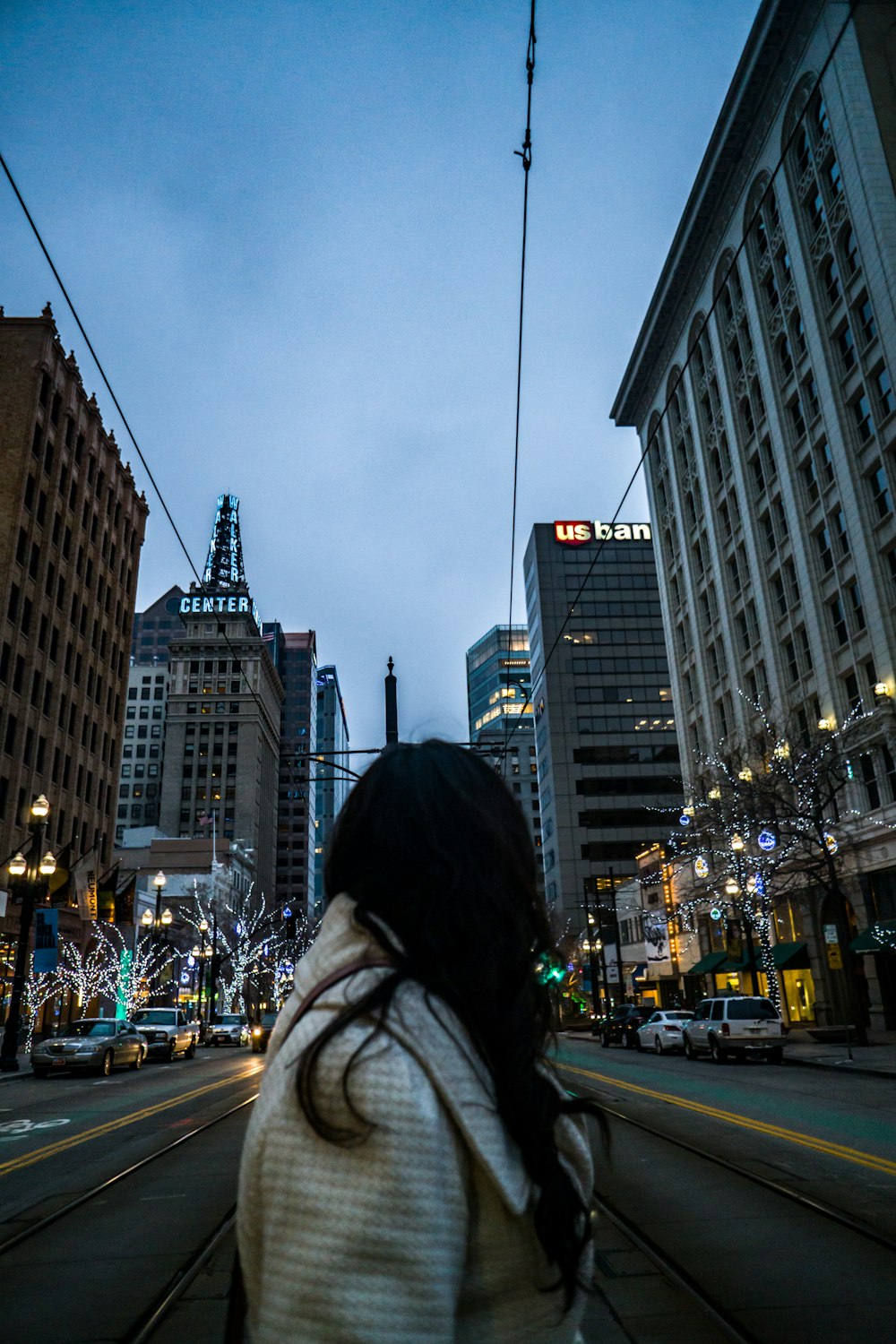 a woman walking down a street next to tall buildings