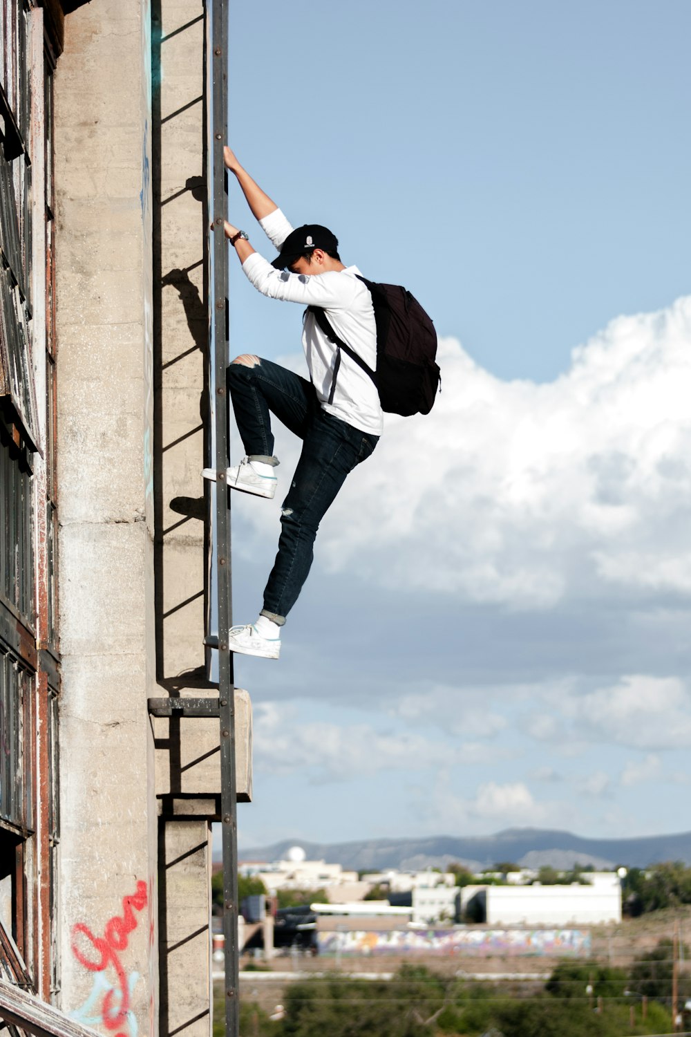 Mann klettert auf Gebäude über Nottreppe