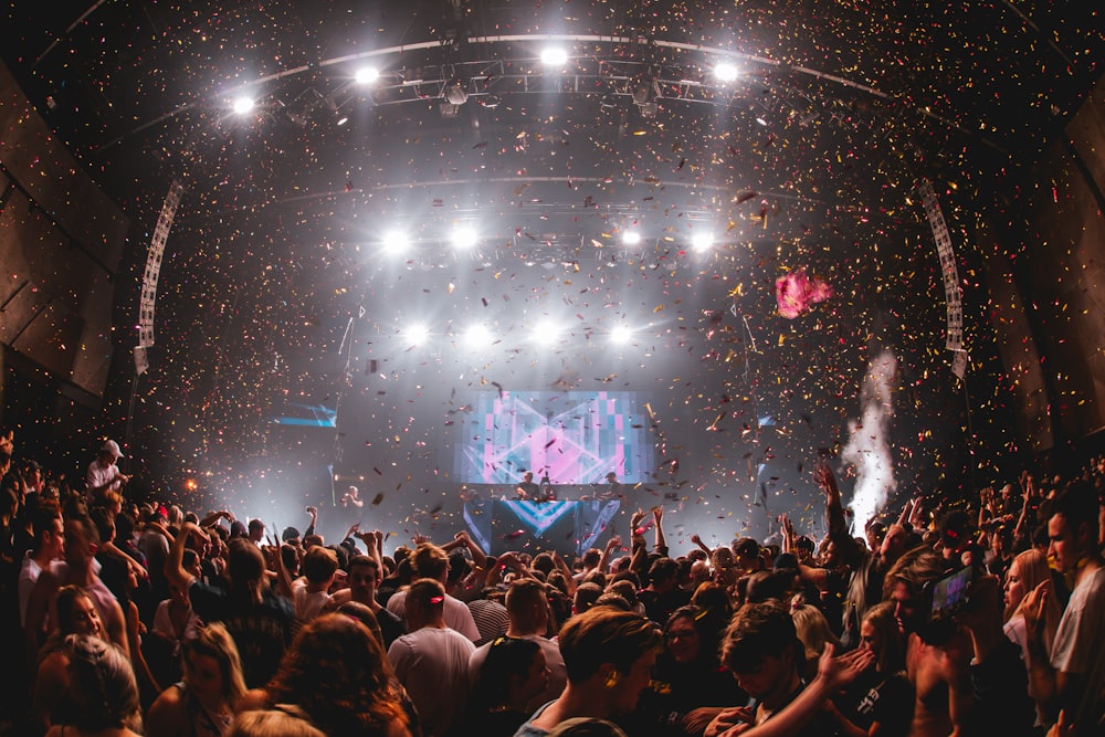 Des confettis tombent d’en haut lors d’un spectacle musical avec une foule immense
