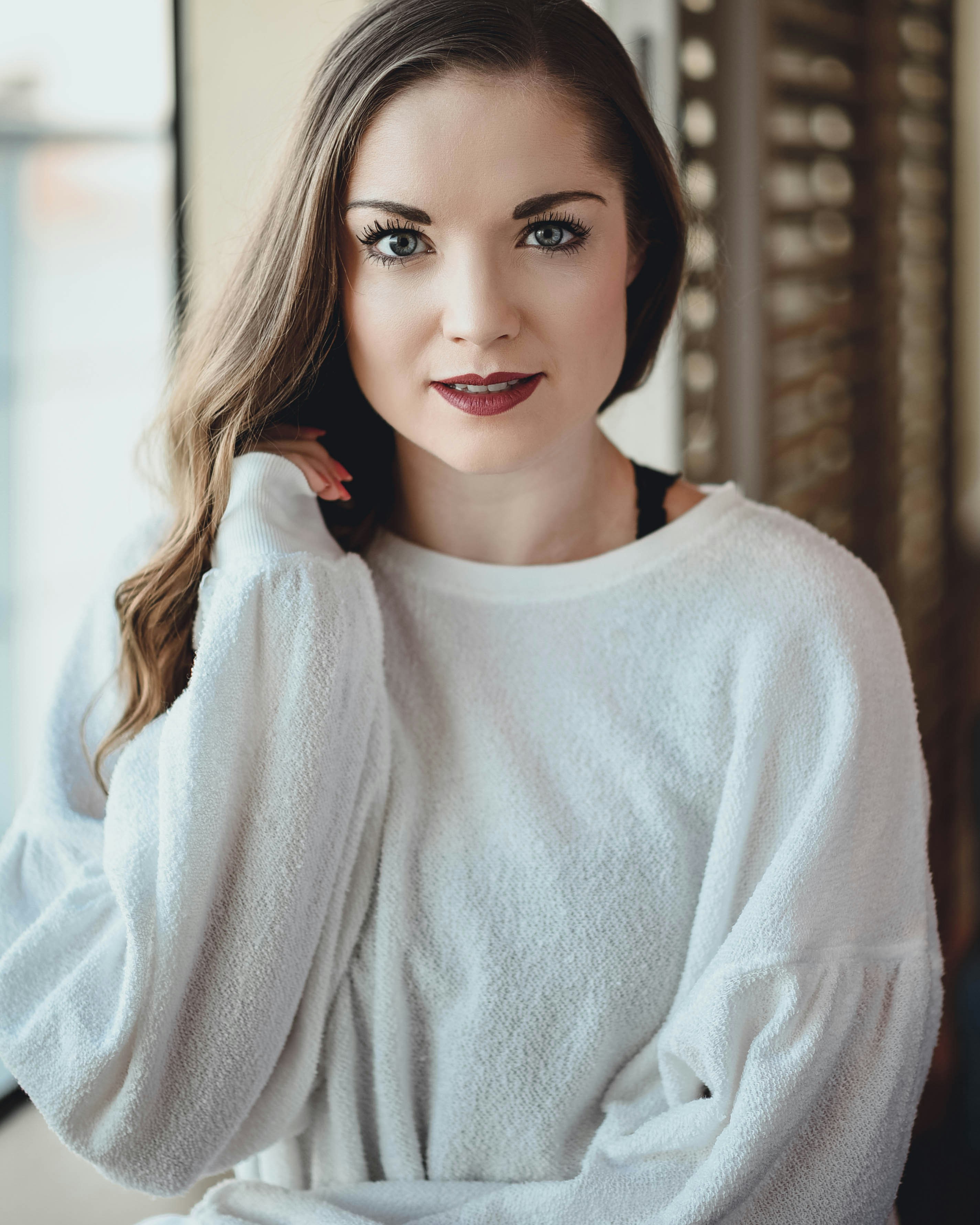 左手を上げている白いトレーナーの女性の写真 Unsplashで見つけるグレーの無料写真