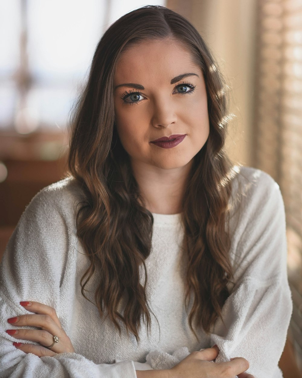 woman in white sweater crossing hands while smiling