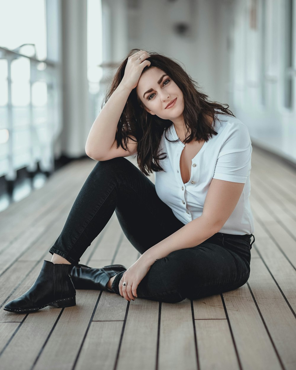 smiling woman in white button-up t-shirt with black pants sitting on floor