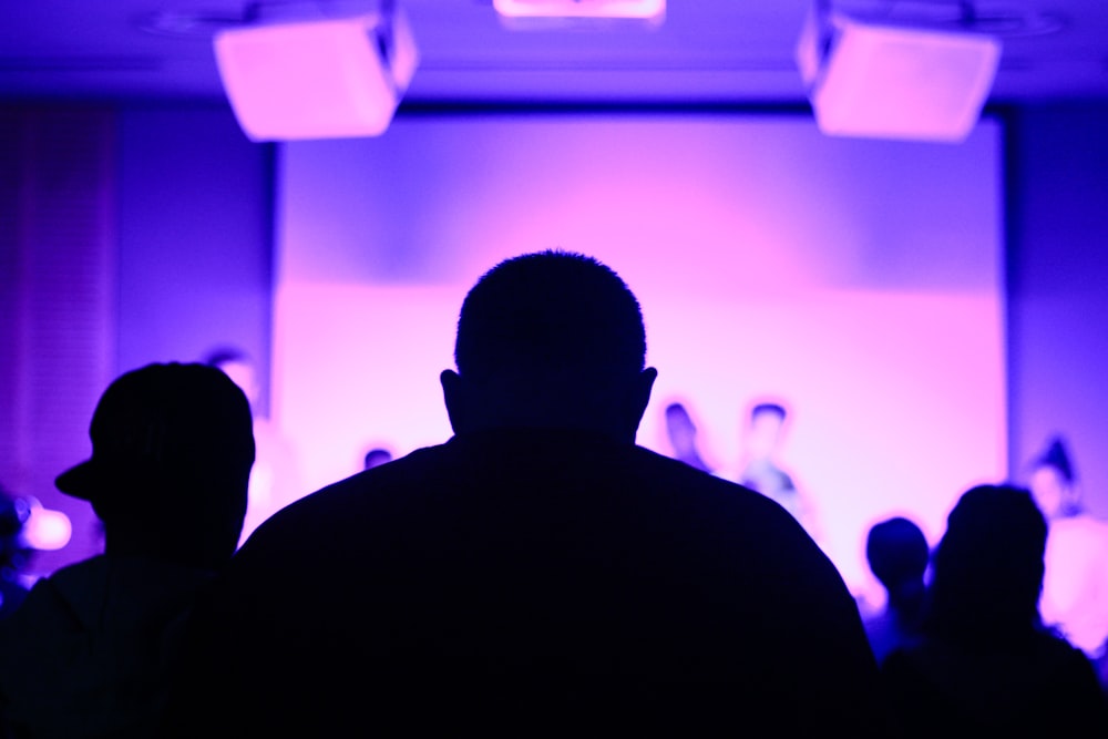 silhouette of three man in front of stage