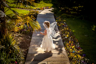 A joyful child dressed as a fairy princess playing in a sunlit garden.