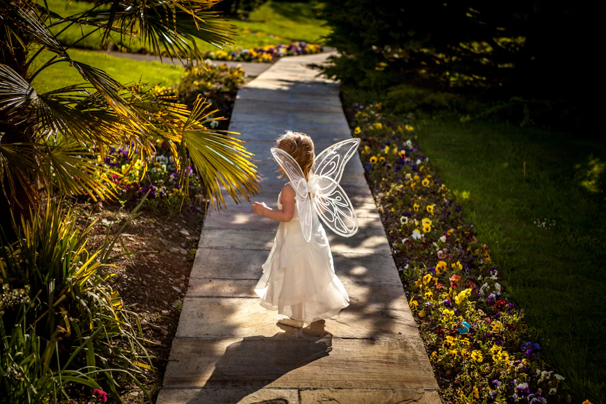 A joyful child dressed as a fairy princess playing in a sunlit garden.
