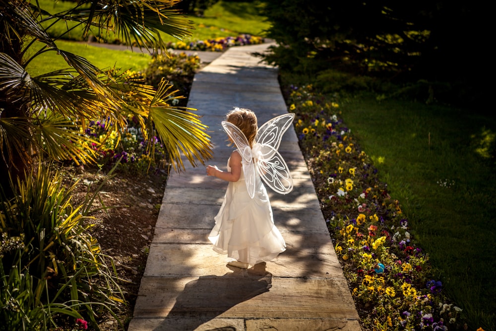 Menina vestindo traje de anjo em pé no caminho de madeira