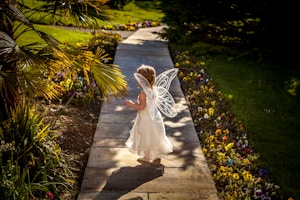 girl wearing angel costume standing on wooden pathway