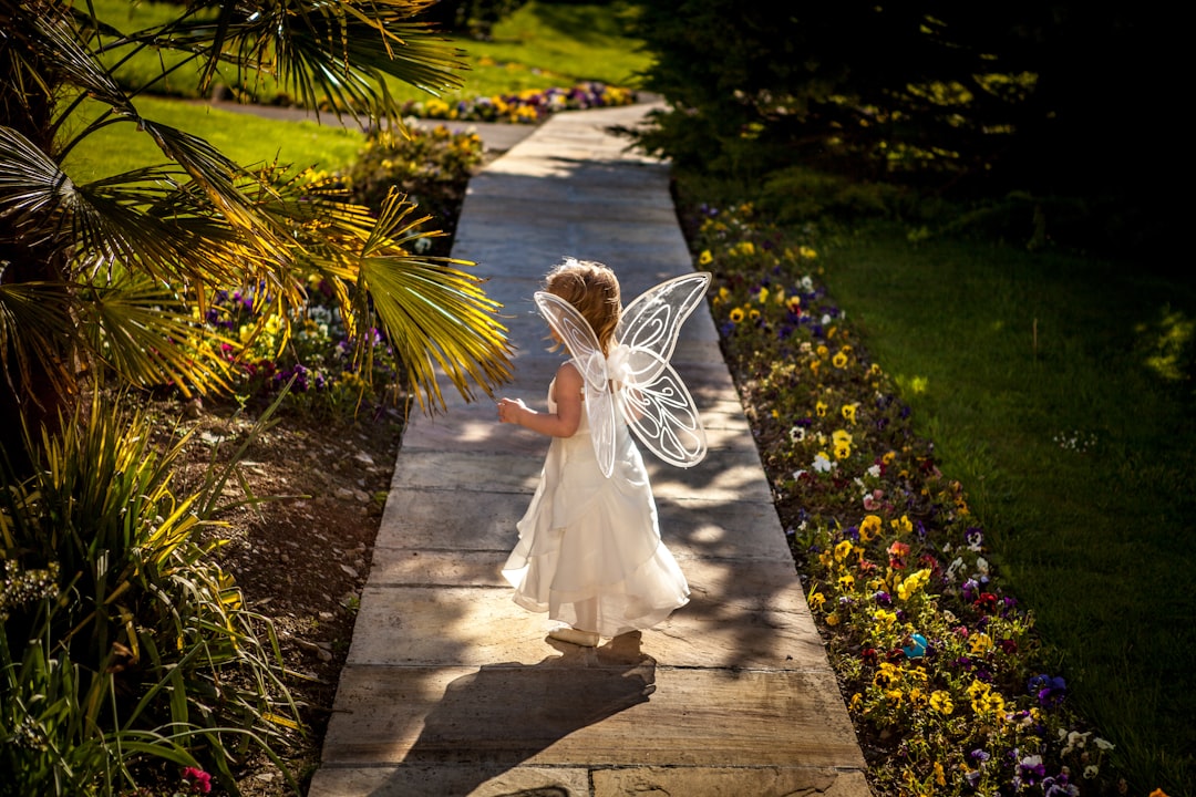 girl wearing angel costume standing on wooden pathway,