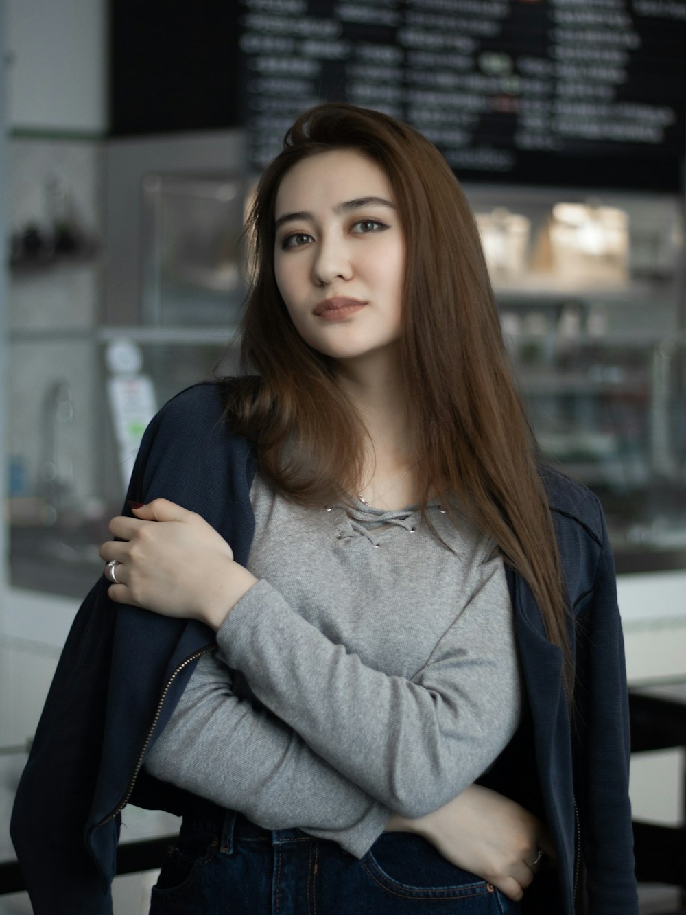 woman wearing gray crew-neck long-sleeved shirt holding shoulder