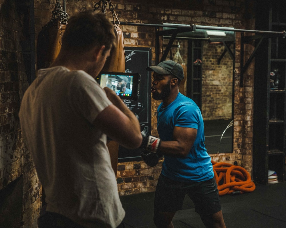 man punching heavy bag near standing man