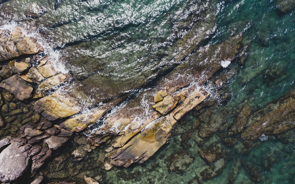 an aerial view of rocks and water near the shore