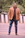 Portrait of a trendy young man in a minimalist brown leather jacket smiling confidently outdoors