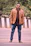 A stylish young man wearing a sleek brown leather jacket from swag, smiling confidently outdoors.