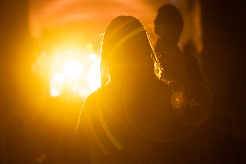 silhouette photography of woman in front of orange light