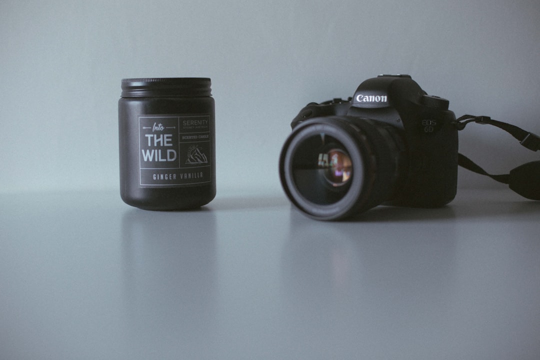 black Canon DSLR camera near black the Wild plastic bottle, New camera and a candle on the desk today!