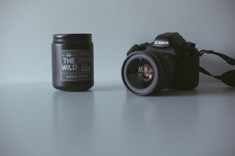 black Canon DSLR camera near black the Wild plastic bottle