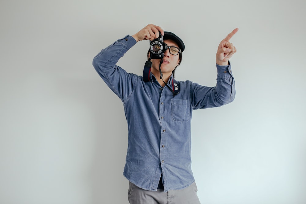 man wearing blue dress shirt holding black DSLR camera