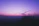 A serene woman smiling softly under a twilight sky with mystical purple hues.