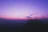 A serene woman smiling softly under a twilight sky with mystical purple hues.