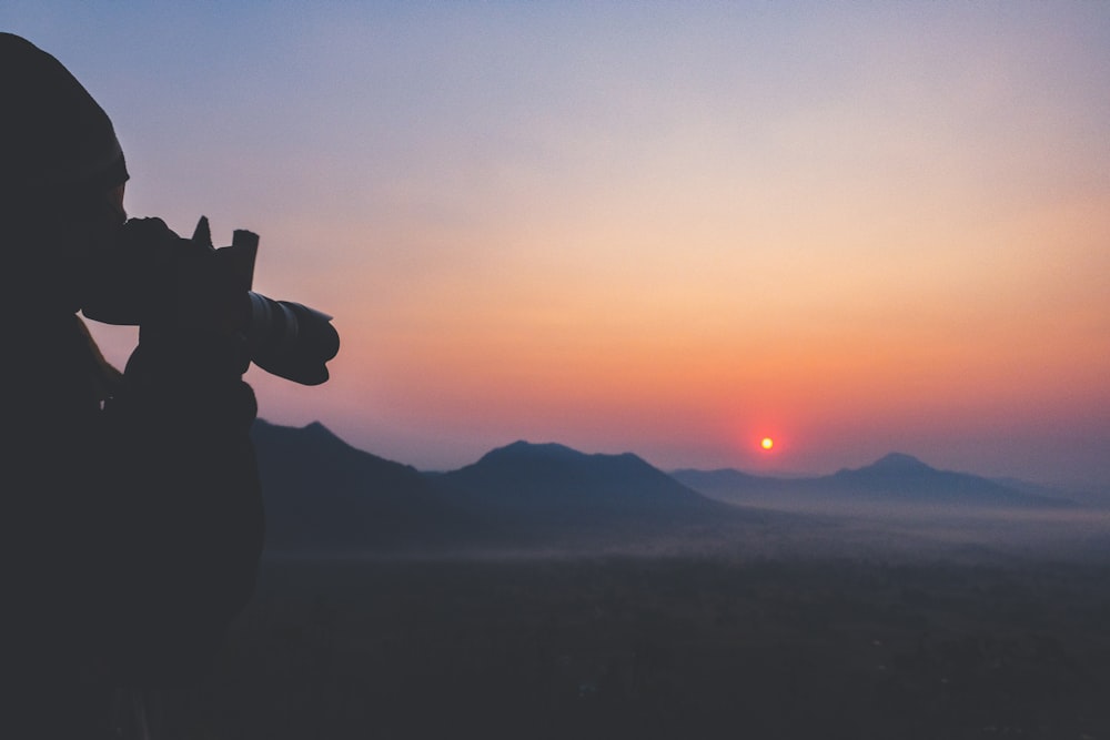 silhouette of person with DSLR camera and zoom lens during golden hour