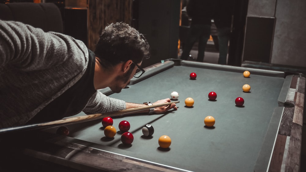 man in grey cardigan playing pool ball