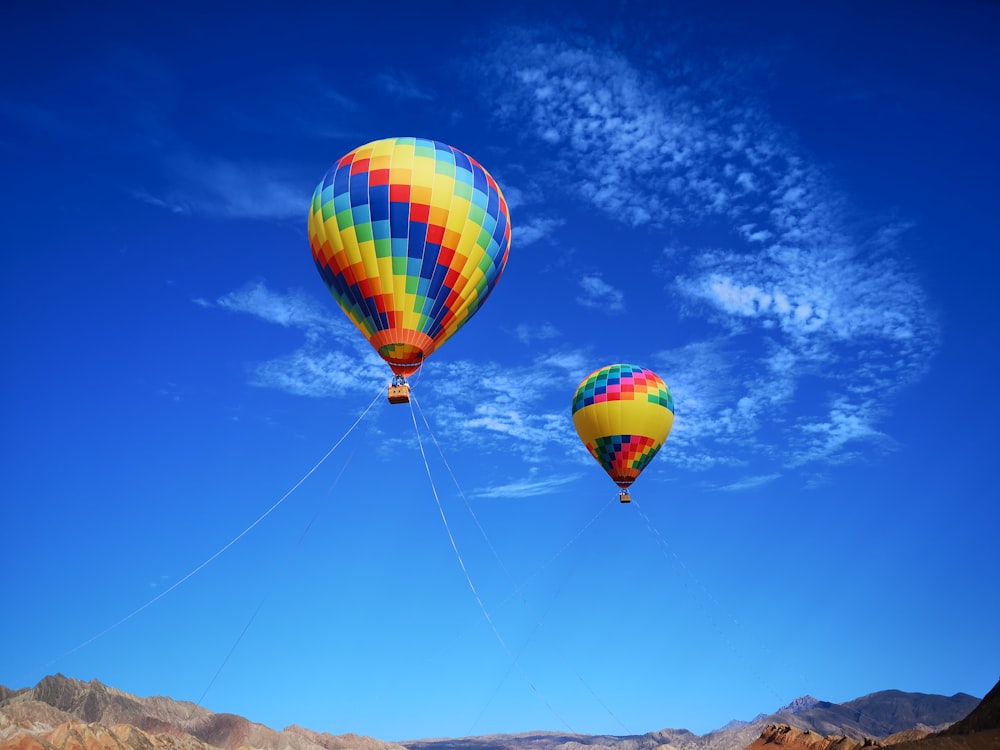 two assorted-color hot air balloons under white and blue sky