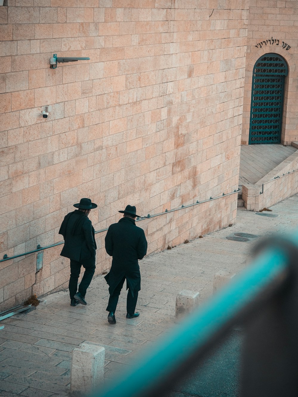 deux personnes portant un costume noir et un chapeau marchant sur le sentier