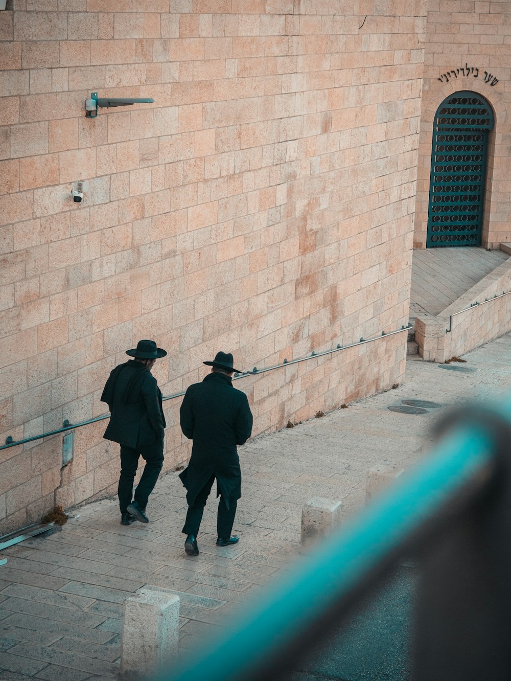 zwei Personen mit schwarzem Anzug und Hut gehen auf dem Weg
