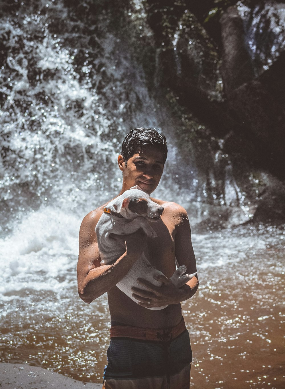 man standing near waterfalls while carrying dog