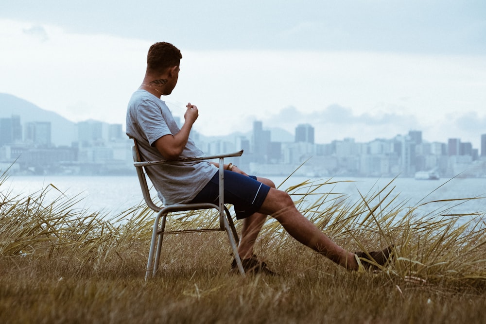 man sitting on armchair while overlooking high-rise buildings during daytime