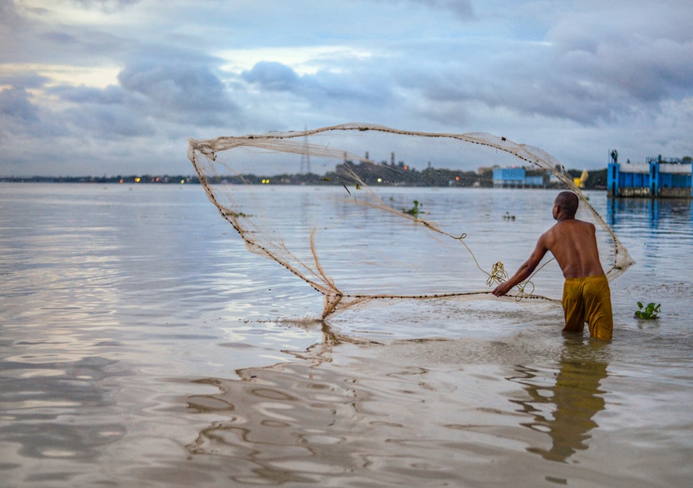 Man spreading fish net on sea photo – Free Grey Image on Unsplash
