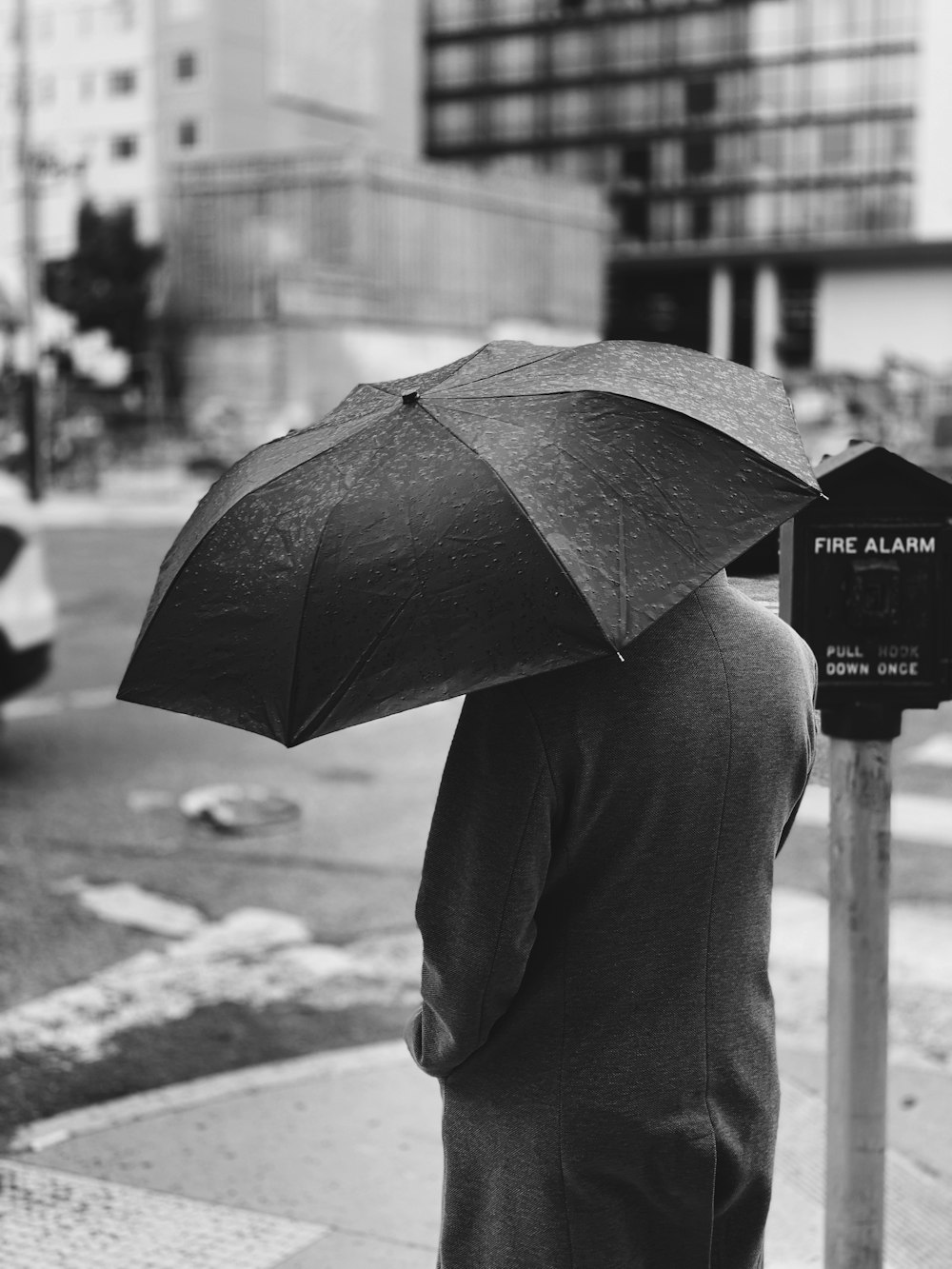 Graustufenfotografie einer Person, die einen Regenschirm hält