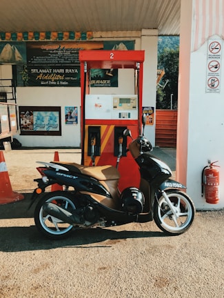 Motorcycle parked beside iconic oil brand containers like Liqui Moly and Agip