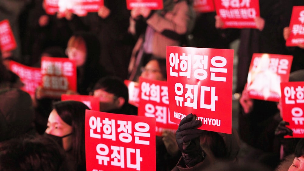 people holding red signages