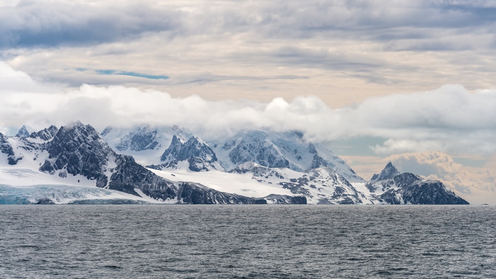 mountain covered with snow near body of water during daytime