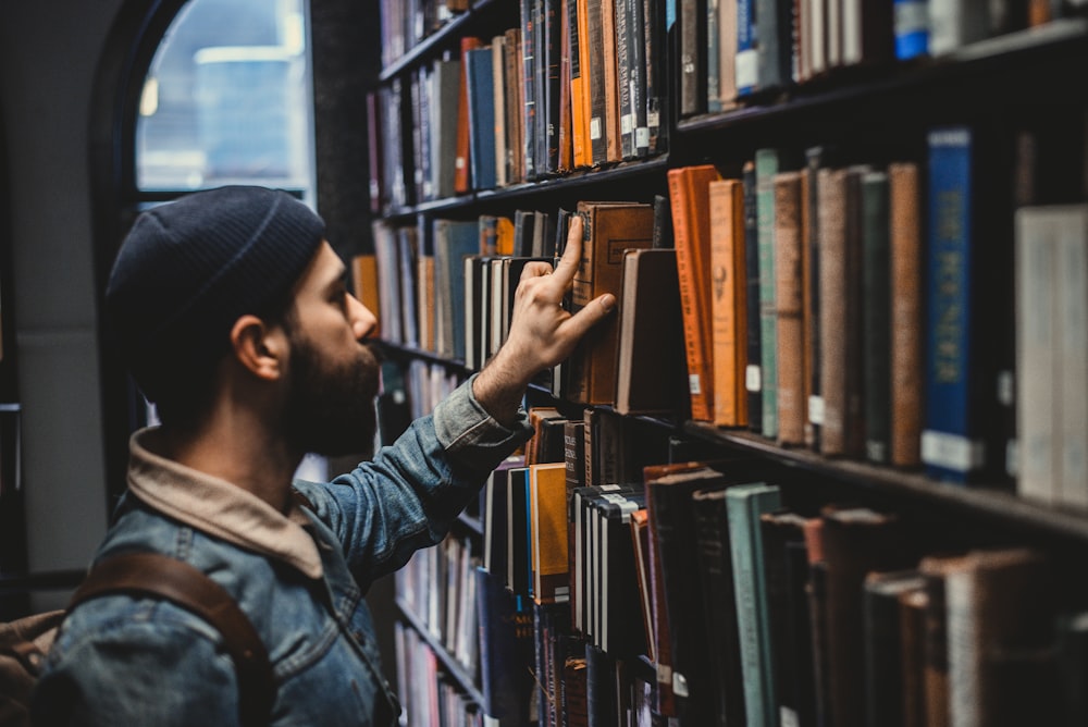 man picking book on bookshelf in library