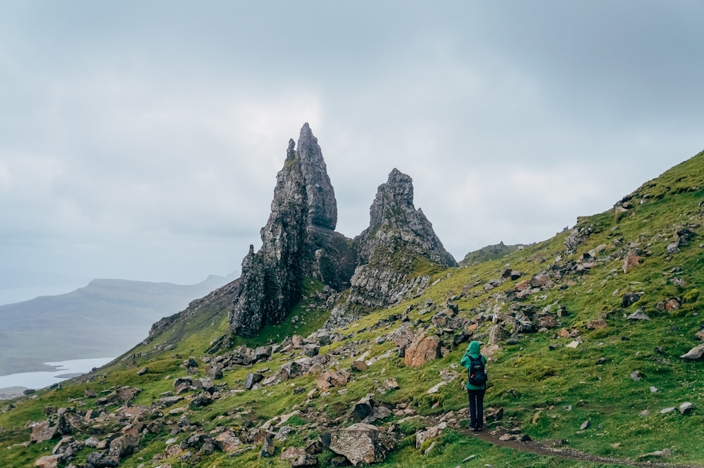 personne en sweat à capuche vert debout sur un champ ouvert vert sous des nuages blancs