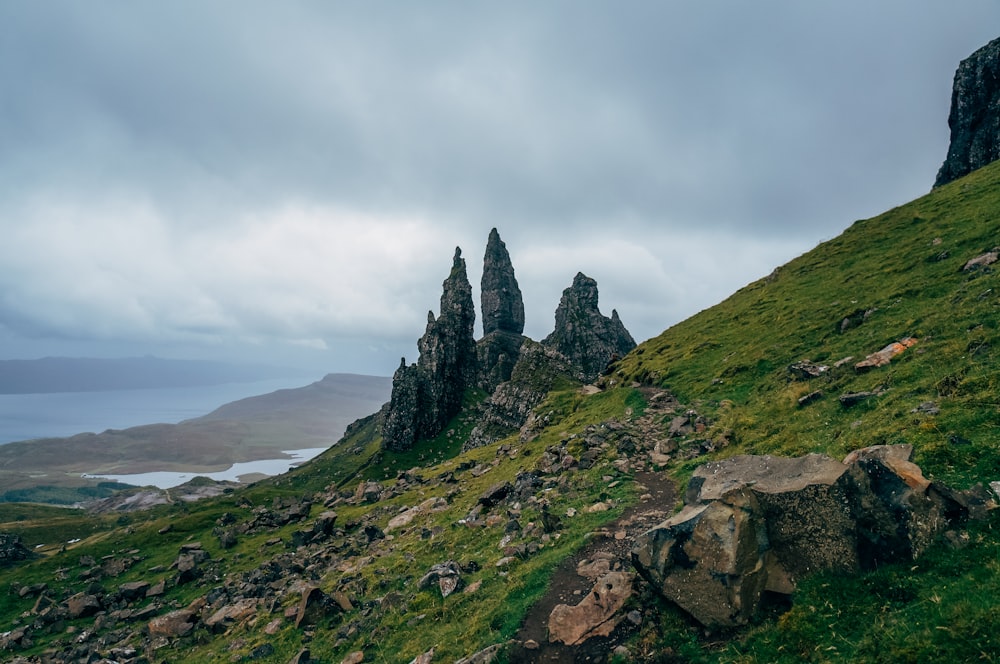 grass covered slope with rock formation on the end under white skies