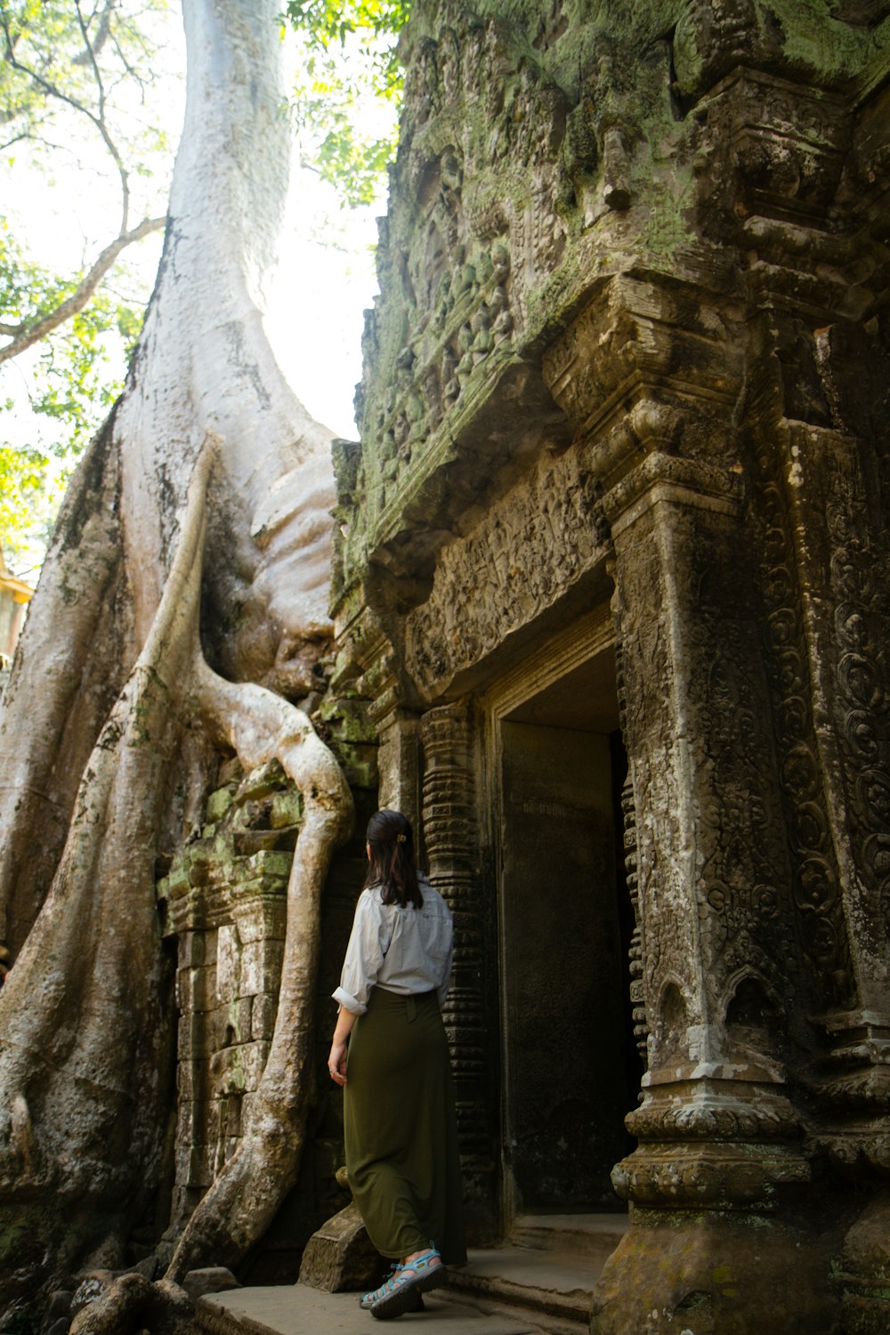 woman standing near concrete door and tree during daytime