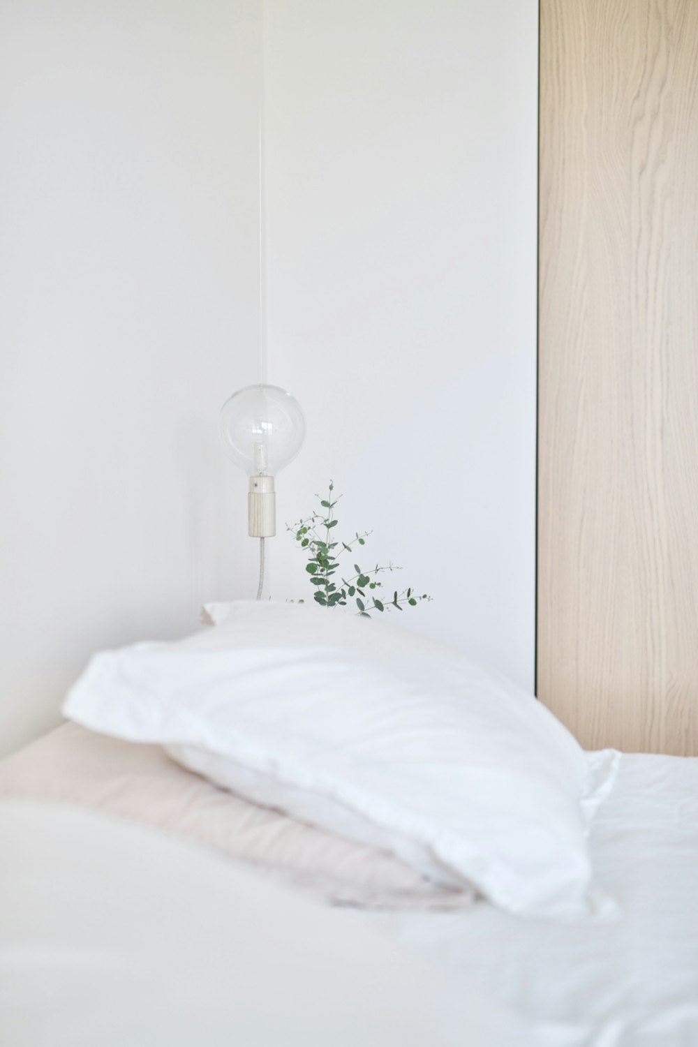 almohada de cama blanca cerca de la lámpara de mesa