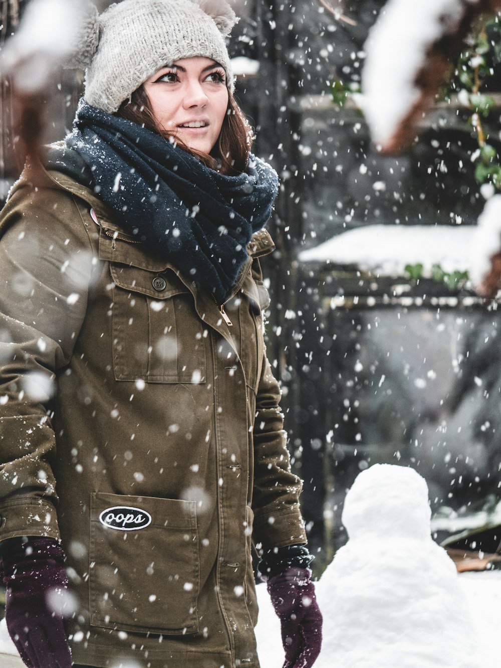 Frau steht auf einem Feld, das mit Schnee bedeckt ist, und Schnee, der herunterfällt,