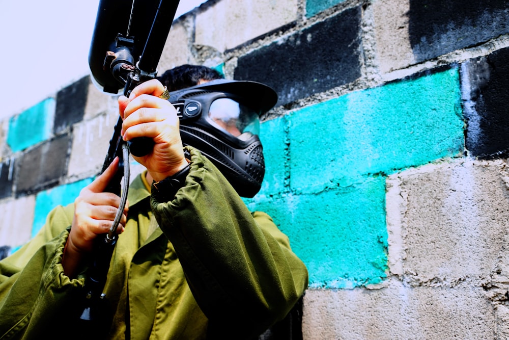 man in green jacket holding paintball gun
