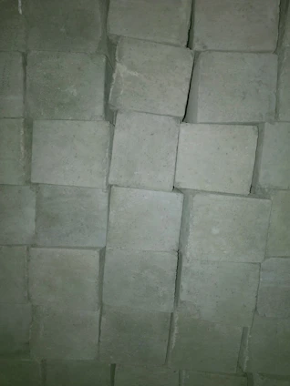 A close-up photo of cement bags stacked neatly in a warehouse with yellow and red branding accents.