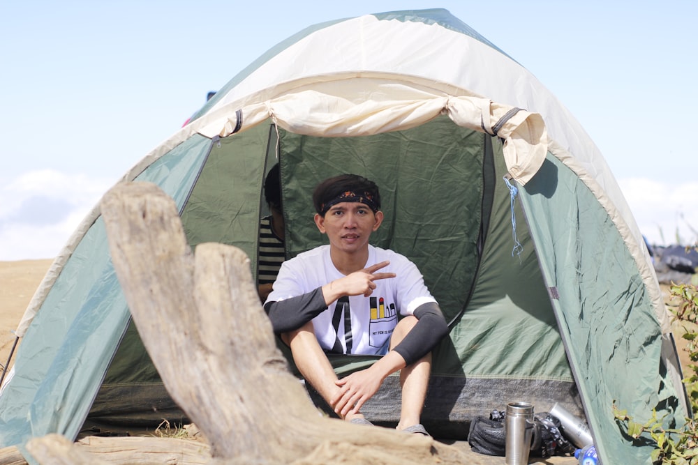man sitting inside tent while posing peace sign