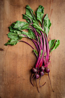 Close-up of vibrant beetroot powder spilling from a rustic wooden spoon onto a natural linen cloth.