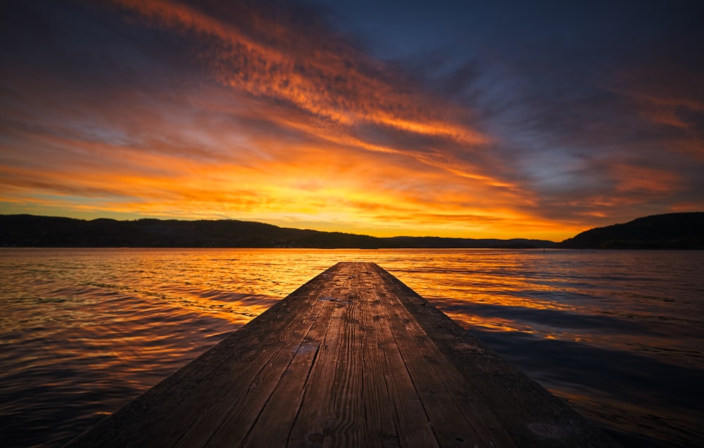 a wooden dock extending into the water at sunset